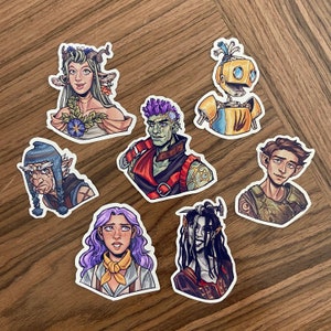 May include: A set of ten colorful stickers featuring various characters. The stickers are printed on white paper and have a glossy finish. The characters include a woman with green hair, a man with purple hair, a robot, a man with brown hair, and a woman with purple hair.