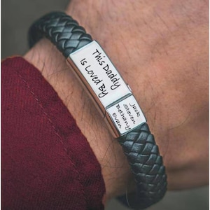 May include: Black leather bracelet with a silver plate engraved with the text "This Daddy is Loved By" and the names Jack, Steven, Bethany, and Evan.