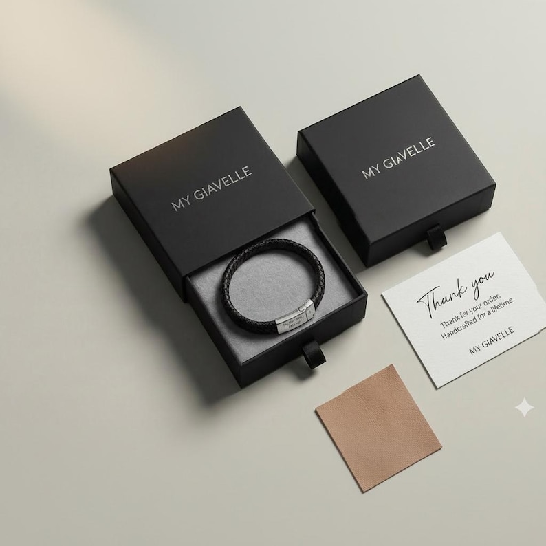 May include: A black leather bracelet with a silver clasp is displayed in an open black box. The box is next to a closed black box and a card that says "Thank you". The brand name "MY GIAVELLE" is printed on the boxes and card.