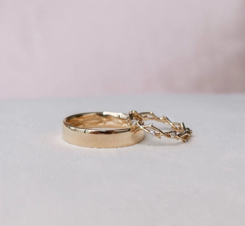 May include: Two gold wedding bands, one with a simple polished finish and the other with a delicate twig design accented with small diamonds.