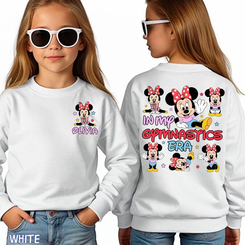 A young girl wearing a white sweatshirt with Minnie Mouse and Minnie Mouse-themed text and graphics on the back.
