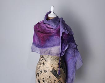 Könnte beinhalten: Handgefertigter, violetter Filzschal mit Farbverlauf, drapiert auf einer Schaufensterpuppe. Der Schal wechselt von tiefem Magenta zu helleren Violetttönen. Die Schaufensterpuppe ist mit Zeitungsdruck bedeckt.