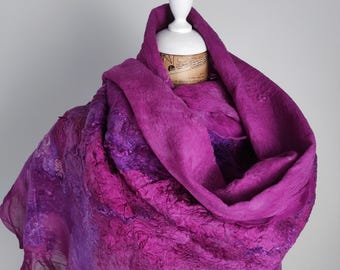 Könnte beinhalten: Ein lebendiger, strukturierter Schal in Lilatönen, drapiert auf einer Schaufensterpuppe. Der Schal hat ein mehrschichtiges Design mit zerknittertem Aussehen, das Tiefe und visuelles Interesse erzeugt. Die Kanten haben eine zarte, transparente Qualität.