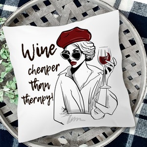 May include: White throw pillow with a black and white illustration of a woman with red hair wearing a red beret and holding a glass of wine. The text "Wine cheaper than therapy!" is printed on the pillow.