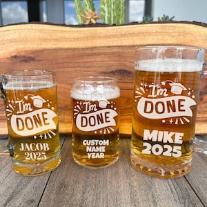 May include: Three glass beer mugs with the text "I'm Done" and a graduation cap design. The mugs are filled with a light brown liquid. The mug on the left says "Jacob 2025", the middle mug says "Custom Name Year", and the mug on the right says "Mike 2025".