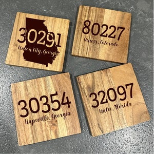 May include: Four square wooden coasters with engraved text. Each coaster displays a different zip code and city: 30291 Union City, Georgia; 80227 Denver, Colorado; 30354 Hapeville, Georgia; and 32097 Yulee, Florida.