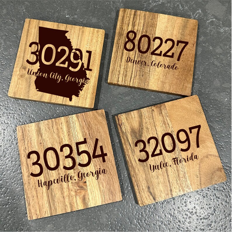 May include: Four square wooden coasters with engraved text. Each coaster displays a different zip code and city: 30291 Union City, Georgia; 80227 Denver, Colorado; 30354 Hapeville, Georgia; and 32097 Yulee, Florida.