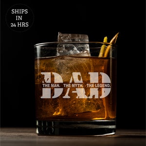 May include: A clear glass with a brown liquid and ice cubes. The glass has the words "DAD THE MAN. THE MYTH. THE LEGEND." etched on the side.