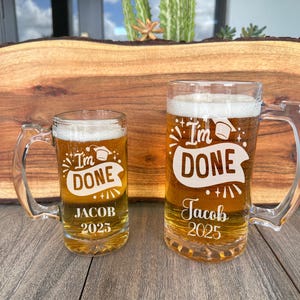 May include: Two glass beer mugs with handles. The mugs are etched with the text "I'm Done" and "Jacob 2025".
