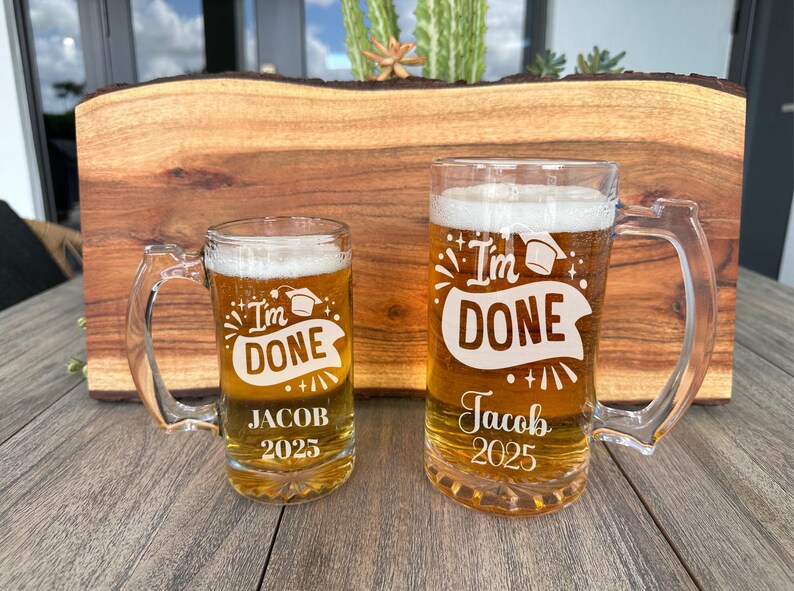 May include: Two glass beer mugs with handles. The mugs are etched with the text "I'm Done" and "Jacob 2025".