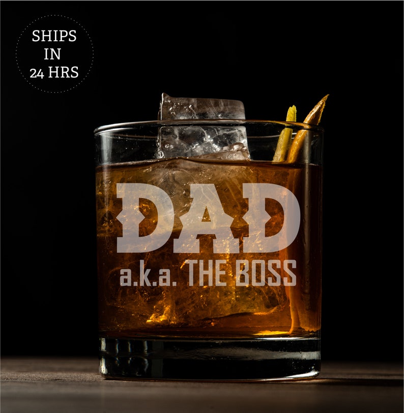 May include: A clear glass with ice and a brown liquid. The glass has the text "DAD a.k.a. THE BOSS" etched on the front.