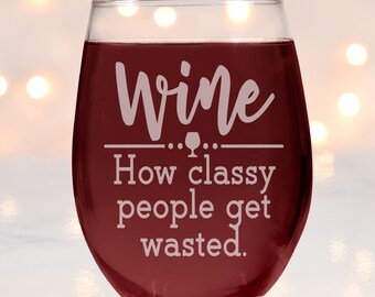 May include: A clear glass wine glass with a red wine inside. The glass has a white inscription that reads "Wine... How classy people get wasted."