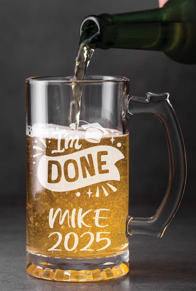 May include: A clear glass beer mug with a handle, filled with a golden liquid. The mug has the text "I'm Done" with a graduation cap above the text, and "Mike 2025" below the text.