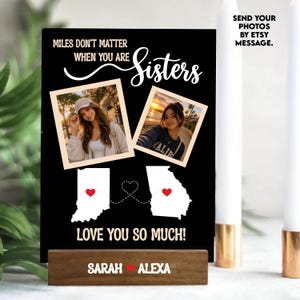 May include: A black wooden sign with the text "MILES DON'T MATTER WHEN YOU ARE Sisters." Two photos are displayed above the states of Indiana and Georgia, connected by a dotted line. The sign reads "LOVE YOU SO MUCH!" and "SARAH ❤️ ALEXA."
