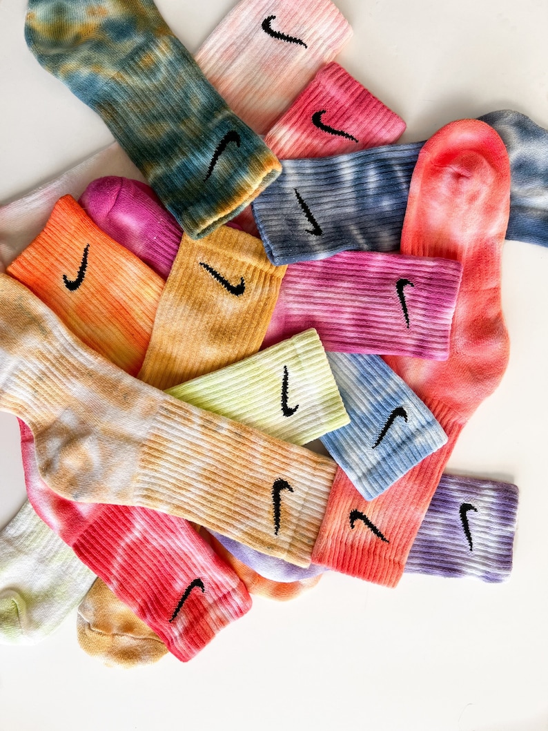 May include: A pile of colorful tie-dye socks with a black Nike swoosh logo on each sock.