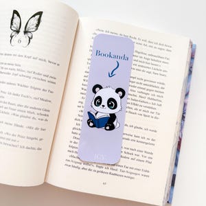 Op de afbeelding: Een lila bladwijzer met de tekst "Bookanda" en een cartoon panda die een boek leest. De bladwijzer staat in een open boek. De bladwijzer heeft het woord "ICY" onderaan. Het boek is open op pagina 65.