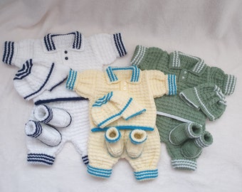 May include: Three knitted baby outfits in white, yellow, and green. Each outfit includes a shirt, trousers, booties, and a hat. The shirts have a polo collar and stripes around the collar and sleeves. The outfits are made with a soft, textured yarn.