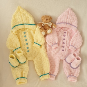 May include: Two knitted baby outfits, one yellow and one pink, with matching booties. Both outfits have a hood and button closure. A small teddy bear is in the center of the image.