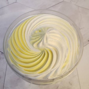 May include: A glass jar filled with a swirl of white and yellow whipped cream.
