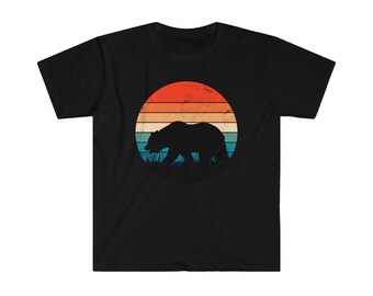 May include: A black t-shirt with a vintage-style graphic of a bear walking in front of a sunset. The sunset is a circle with red, orange, yellow, and blue stripes.