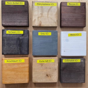 May include: Nine wooden blocks with different stain colors are displayed. The colors include dark brown, light beige, dark brown, black, gray, white, light orange, light beige, and dark brown. Each block has a yellow label with a color name.