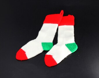 Vintage acrylic knit Christmas stockings; white with red toe, green heel, red ribbing at the top, red yarn loop.