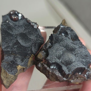 May include: Two pieces of black hematite with a rough, textured surface. The hematite has a metallic sheen and is irregularly shaped.
