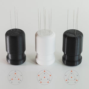 May include: Three 3D printed bases with a circular pattern of pins on top. The bases are black, white, and black. The pins are arranged in a geometric pattern, with a triangle in the centre.