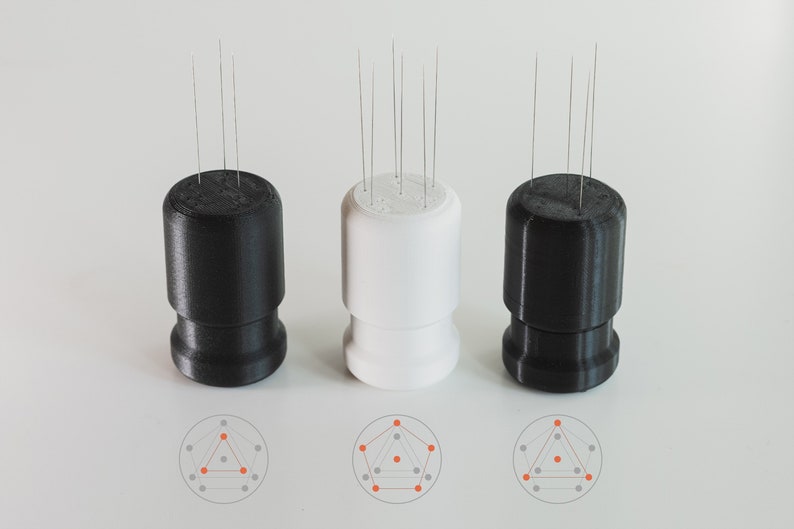 May include: Three 3D printed bases with a circular pattern of pins on top. The bases are black, white, and black. The pins are arranged in a geometric pattern, with a triangle in the centre.