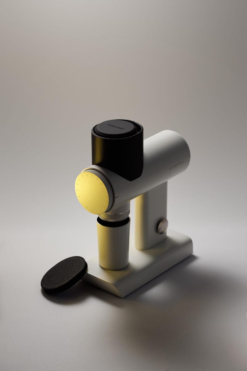 May include: A white and black device with a cylindrical body and a circular light. The device has a base and a small, black, circular object next to it. The text "NITROPRESS" is visible on the top.