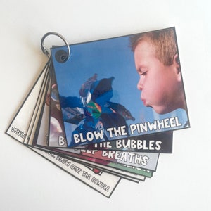 K&ouml;nnte beinhalten: Ein Satz bunter Karten mit Bildern und Text. Die Karten sind mit einem silbernen Ring verbunden. Der Text auf den Karten lautet "Dreh die Windm&uuml;hle an", "Blase die Seifenblasen", "Tiefe Atemz&uuml;ge" und "Blase die Kerze aus".