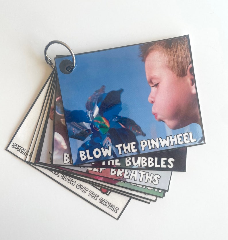 K&ouml;nnte beinhalten: Ein Satz bunter Karten mit Bildern und Text. Die Karten sind mit einem silbernen Ring verbunden. Der Text auf den Karten lautet "Dreh die Windm&uuml;hle an", "Blase die Seifenblasen", "Tiefe Atemz&uuml;ge" und "Blase die Kerze aus".