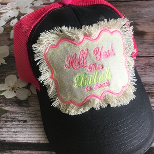 May include: Black and pink trucker hat with a frayed, beige patch that says "Hell Yeah This Bitch is Back".