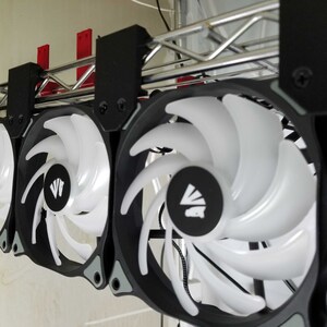 May include: Four black computer fans with white blades and a black and white logo in the center. The fans are mounted on a metal rack.