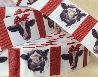 May include: White and red ribbon with a repeating pattern of black and white cows wearing red bandanas. The cows are facing forward and have a white background. The red stripes are a paisley pattern.
