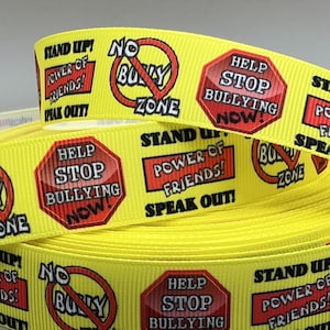 May include: Yellow ribbon with anti-bullying messages in red and black. The ribbon repeats phrases like "No Bully Zone," "Help Stop Bullying Now," and "Stand Up! Power of Friends! Speak Out!"