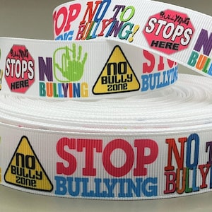 May include: White ribbon with the words "STOP BULLYING" in various colors. The ribbon also features a handprint, a stop sign, and a "NO BULLY ZONE" sign. The ribbon is rolled up in a coil.