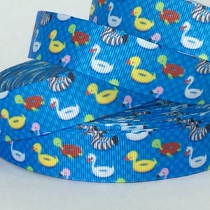 May include: A roll of blue ribbon with a repeating pattern of colorful inflatable pool toys, including ducks, swans, and flamingos.