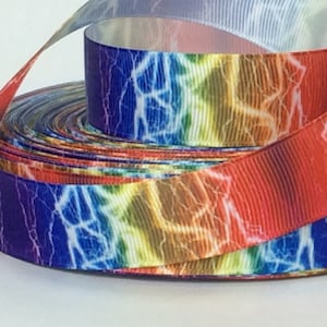 May include: A roll of rainbow-colored ribbon with a lightning bolt pattern. The ribbon is made of satin and has a shiny finish.