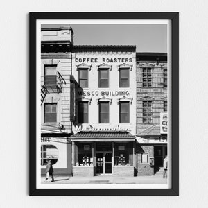 May include: Black and white photograph of a building with a sign that reads "Coffee Roasters" and "Mesco Building".