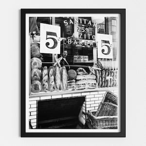 May include: Black and white photo of a bakery storefront with a sign that reads "Sanitary 259 A. Zito Bakery" and two signs that read "5c". The storefront window is filled with loaves of bread.