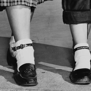 May include: Two pairs of white socks with black ankle straps, worn with black shoes. One pair of socks has a silver beaded ankle strap.