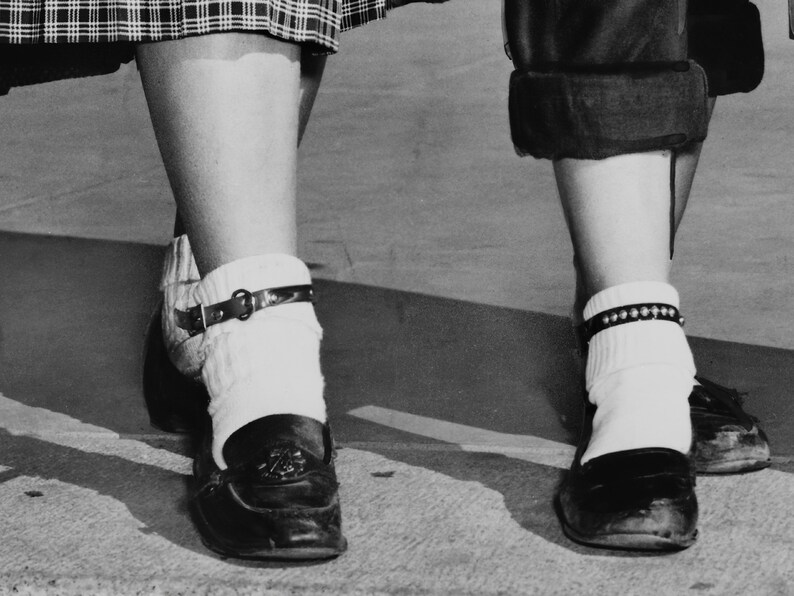 May include: Two pairs of white socks with black ankle straps, worn with black shoes. One pair of socks has a silver beaded ankle strap.
