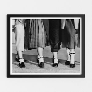 May include: Black and white photo of four women's legs wearing white socks and black shoes with buckles. The women are wearing skirts and pants.