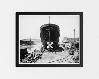 May include: A black and white photo of a large ship in dry dock. The ship is named "William Coyt" and has a large propeller visible. The ship is surrounded by wooden beams and other construction materials.
