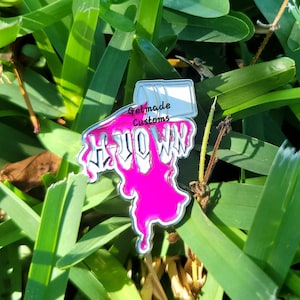 May include: Pink enamel pin with the words "Hello Win" dripping from a white paint can. The paint can has the text "Getmade Customs" on it.