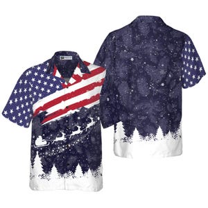 May include: Short-sleeved button-up shirt featuring a festive design. The front displays the American flag with a winter scene of Santa's sleigh and reindeer. The back has a navy blue pattern with white trees and snowflakes.