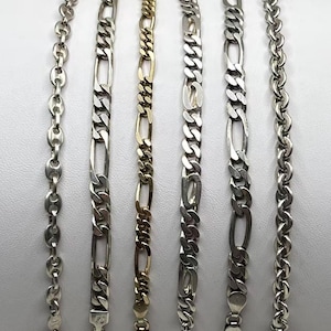 May include: Six metal chain bracelets arranged vertically and numbered one through six. The collection includes silver-toned anchor, figaro, and curb link styles, alongside one gold-toned figaro chain, each featuring a secure lobster claw clasp.