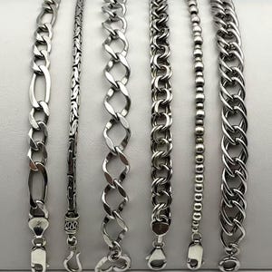 May include: Six silver-toned metal chain bracelets arranged vertically and numbered one through six. The collection includes various link styles such as Figaro, wheat, twisted oval, double link, beaded, and curb chain designs with metal clasps.