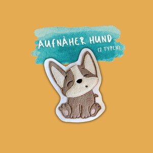 Könnte beinhalten: Ein gestickter Bügelaufkleber mit einem braunen und weißen Hund mit dem Text "AUFNÄHER HUND (2 TYPEN)" auf einem blauen Aquarellhintergrund.